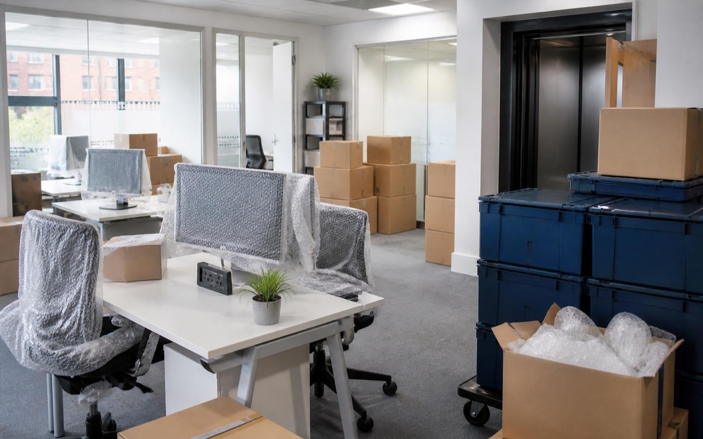 Office desks, protected monitors and moving crates prepared for a commercial move
