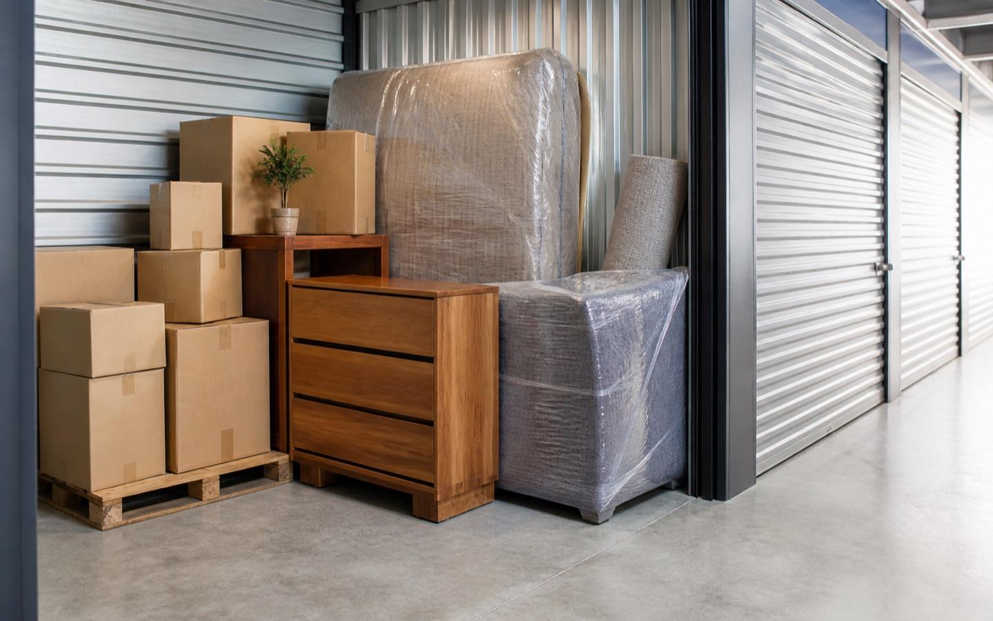 Wrapped household furniture and boxes stored neatly in a secure storage unit