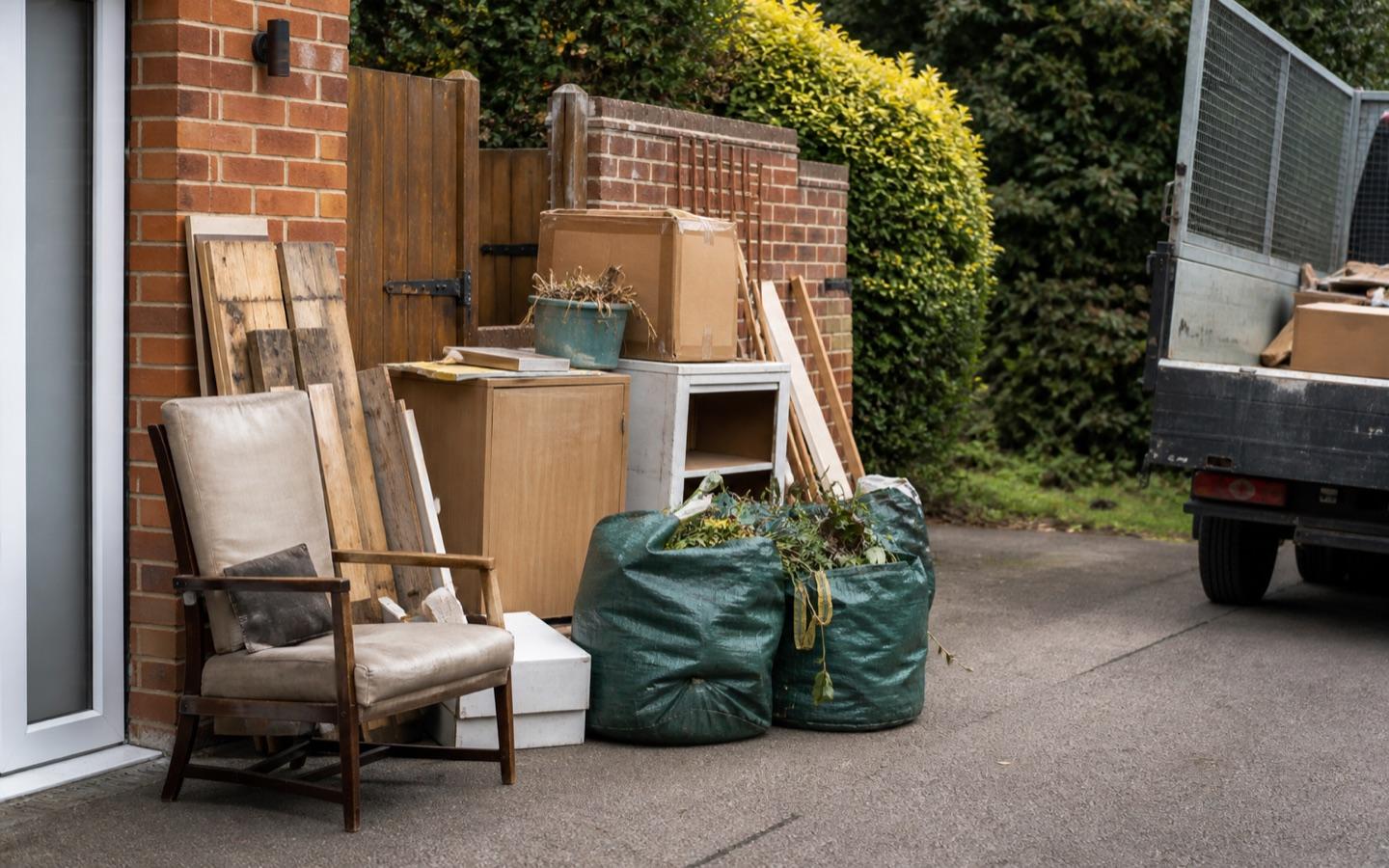 Household waste and garden bags stacked neatly on a driveway for licensed collection