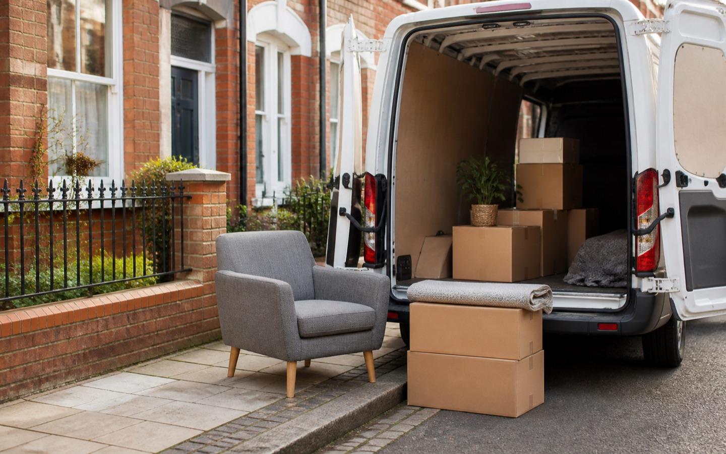Small move with boxes and an armchair ready beside an open unbranded van